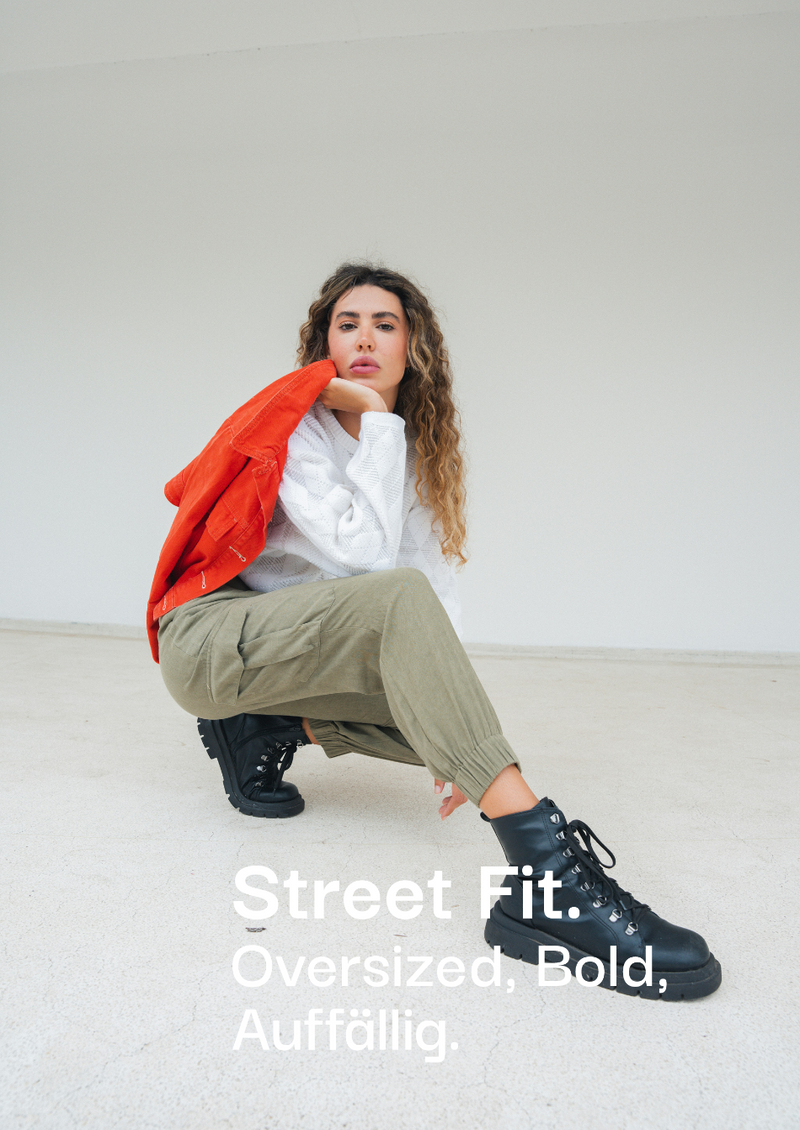 Auffälliger Street Fit Look bei sneekrs mit Cargo-Hose, roter Jacke und schwarzen Boots